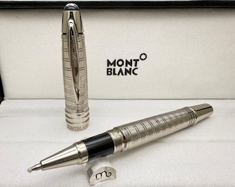 May include: A silver Montblanc rollerball pen with a black ink cartridge, displayed in a white box. The pen has a textured, grid-like pattern on the barrel and cap, with a black grip. The Montblanc logo is visible.