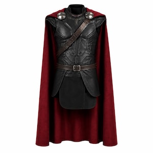May include: A black leather-look chest armour piece with a high collar, featuring a brown diagonal strap and a matching waist belt with a silver buckle. A long, deep red cape is attached at the shoulders with two large, circular silver-toned metal discs.