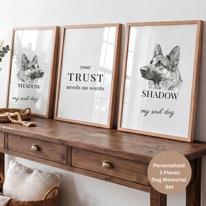 Könnte beinhalten: Ein Set aus drei gerahmten Wandbildern mit hellen Holzrahmen. Zwei Bilder zeigen eine schwarz-weiße Skizze eines Deutschen Schäferhundes mit dem Text SHADOW und my soul dog. Das mittlere Bild zeigt den Text your TRUST needs no words.