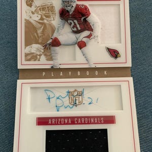May include: An Arizona Cardinals football card featuring Patrick Peterson. The card has a photo of Peterson in action, a facsimile signature, and the team logo. The word "PLAYBOOK" is printed at the bottom.
