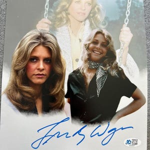 May include: A signed photograph featuring three images of a woman with long, wavy blonde hair. She is wearing a black top and a patterned scarf in one image. The signature is in blue ink. A small authentication sticker is in the bottom right corner.