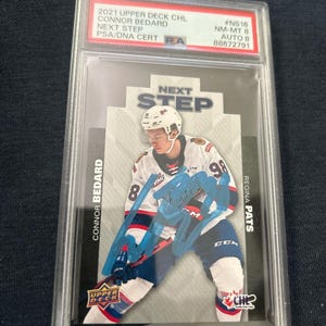 Könnte beinhalten: Eine Hockey-Sammelkarte mit Connor Bedard im Trikot der Regina Pats. Die Karte befindet sich in einer Schutzhülle und trägt den Text "2021 Upper Deck CHL Next Step" und "PSA/DNA CERT".