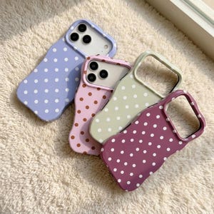 May include: Four colorful phone cases with a wavy design and polka dots. The cases are in shades of lavender, pink, green, and burgundy, each with a different color of polka dots. The cases are designed to fit a smartphone.