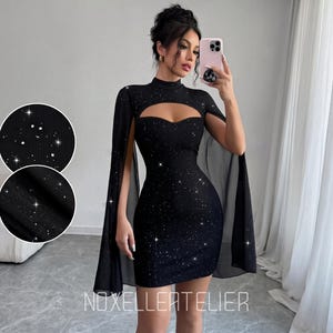 May include: A black mini dress featuring a high neckline, a sweetheart-shaped cutout at the chest, and long, flowing cape-style sleeves. The fabric is covered in a subtle, shimmering glitter pattern that catches the light. The text NOXELLERATELIER is visible.
