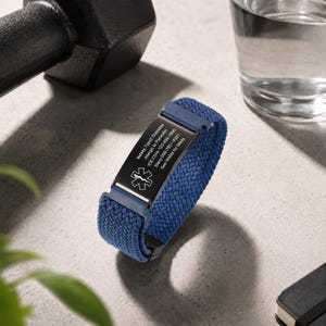 May include: A blue woven elastic medical alert bracelet featuring a black rectangular metal plate engraved with a white Star of Life symbol and text including Kelsey, Type 2 Diabetes, Allergic to Penicillin, ICE: Chris 123-456-7890, Stacy 098-765-4321, See Wallet for Meds.