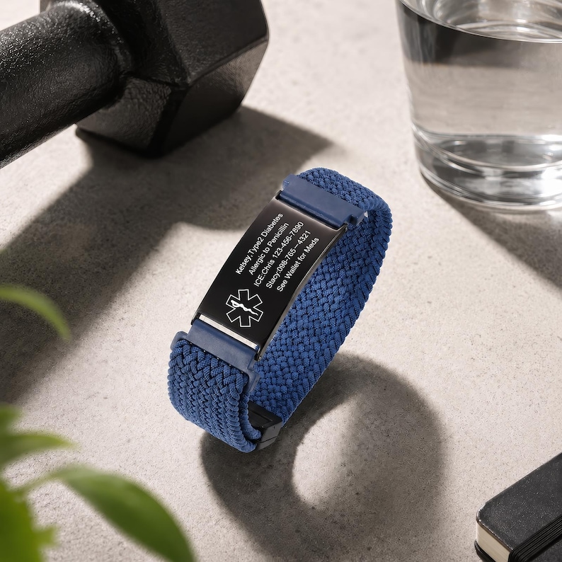 May include: A blue woven elastic medical alert bracelet featuring a black rectangular metal plate engraved with a white Star of Life symbol and text including Kelsey, Type 2 Diabetes, Allergic to Penicillin, ICE: Chris 123-456-7890, Stacy 098-765-4321, See Wallet for Meds.