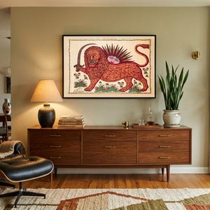 May include: A framed wall art print featuring a stylized illustration of a lion holding a curved sword, with a sun-like face on its back, set against a cream background with floral accents and a decorative border in a black frame.