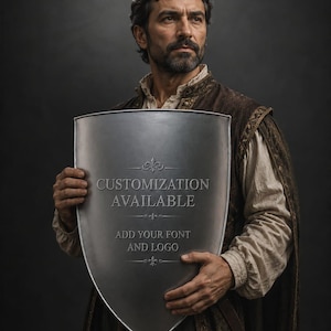 Pode incluir: Um escudo prateado com o texto "PERSONALIZAÇÃO DISPONÍVEL" e "ADICIONE SUA FONTE E LOGOTIPO". O escudo é segurado por uma pessoa vestida com uma roupa medieval marrom e dourada contra um fundo escuro.