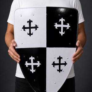 May include: A black and white shield with a cross design. The shield is divided into four quadrants, with alternating black and white sections. Each section features a white cross. The shield is held by a person.