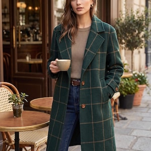 Puede incluir: Un abrigo verde oscuro de mezcla de lana con un patrón de cuadros marrón, solapas de muesca y dos botones marrones. El abrigo se lleva sobre una camiseta de manga larga acanalada de color beige, un cinturón de cuero marrón y vaqueros azul oscuro.