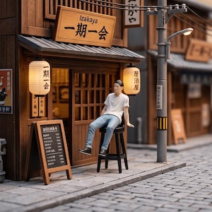 Könnte beinhalten: Ein Miniatur-Diorama einer japanischen Izakaya-Fassade mit einem Holzgebäude, einem Schild mit der Aufschrift Izakaya, zwei beleuchteten Papierlaternen, einer Menütafel und einer kleinen Figur in weißem T-Shirt und blauer Jeans auf einem Hocker.