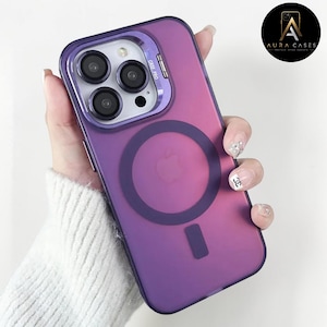 May include: A purple iPhone case with a clear camera lens protector and a magnetic ring on the back. The case has a gradient color effect and a small rectangular cutout at the bottom. The case is designed to protect the phone.