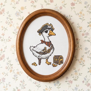 May include: Cross-stitch picture of a goose in a pirate costume, including a hat, eye patch, and sash, with a treasure chest and gold coins. The artwork is in an oval, wooden frame.