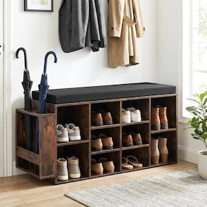 May include: A wooden shoe storage bench with a black cushioned top and multiple cubby shelves. The bench has a dark brown finish and is filled with various shoes. Two umbrellas stand in a side compartment.