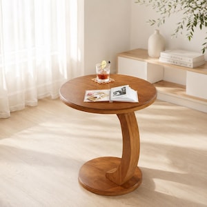 May include: A round wooden side table with a smooth, medium-brown finish, featuring a circular top supported by a single, curved, C-shaped pedestal base that connects to a matching circular floor base, creating a stable and balanced structure.