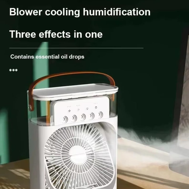 May include: White air cooler with a fan and a brown handle. The device has a clear top section and a control panel with multiple buttons. Text on the image reads: "Blower cooling humidification", "Three effects in one", and "Contains essential oil drops."