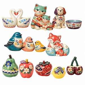 May include: A collection of ceramic figurines featuring two swans, a cat and kitten, a dog, a bowl, three birds, a fox and kit, a pear, an apple, a tomato, a lemon, and cherries, all decorated with colorful floral and geometric patterns.