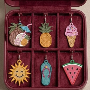 May include: A selection of six vibrant summer-themed earrings presented in a burgundy jewellery box. The earrings showcase designs including a coconut drink, pineapple, ice cream cone, smiling sun, flip-flop, and watermelon slice.
