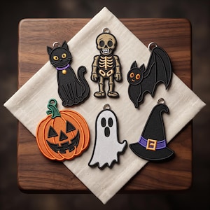 May include: A collection of six Halloween-themed embroidered patches featuring a black cat with a purple collar, a gold skeleton, a black bat, an orange jack-o'-lantern, a white ghost, and a black witch hat with a purple band and gold buckle.