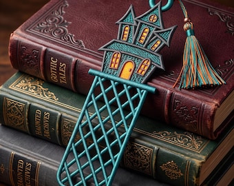 May include: A teal embroidered bookmark shaped like a haunted house with yellow windows and a door, featuring a lattice-patterned base and a matching teal and orange tassel attached to the top ring, resting on a stack of three vintage books.