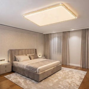 May include: A bedroom featuring a rectangular upholstered bed with a tufted headboard, two matching nightstands with integrated lighting, a large rectangular ceiling light fixture, floor-to-ceiling beige curtains, and a patterned area rug.