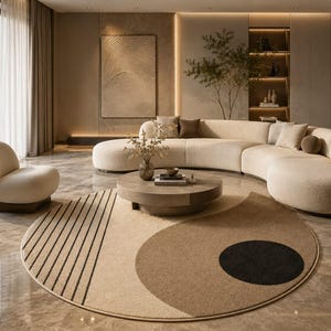 May include: A circular area rug featuring a beige and tan colour palette with a black circular accent and black linear stripes. The rug is positioned in a living space with a curved cream-coloured sofa, a matching armchair, and a round wooden coffee table.