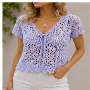 May include: A light purple crochet top with a V-neckline and short sleeves. The top features a tie closure at the neckline and a scalloped hem. The open weave design creates a delicate and airy look.