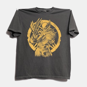 Peut inclure: Un t-shirt gris anthracite à manches courtes avec une impression graphique jaune vieillie représentant le personnage Wolverine avec des griffes étendues, centré dans un emblème circulaire. Le motif a un aspect usé et vintage.