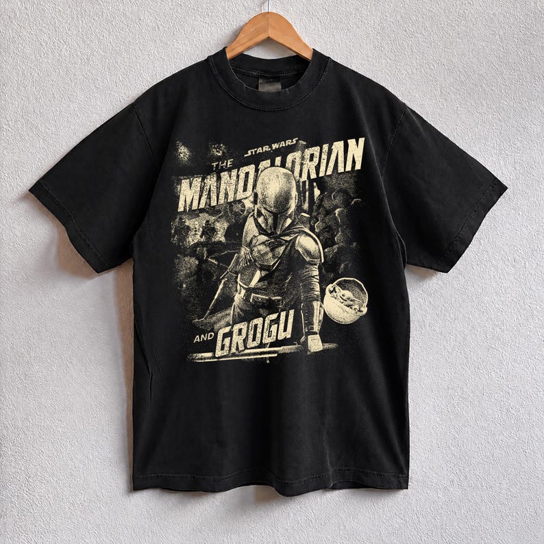 Pu&ograve; includere: T-shirt nera con grafica vintage di The Mandalorian e Grogu di Star Wars. Il design include il testo "THE MANDALORIAN" e "AND GROGU" in stile vintage, con un'immagine di The Mandalorian e Grogu.