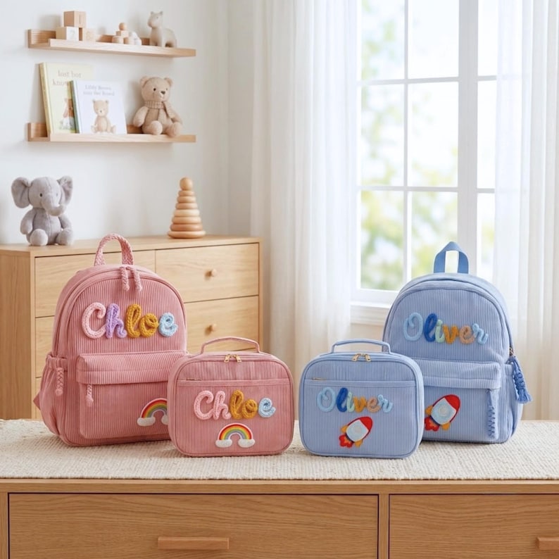 Op de afbeelding: Twee sets corduroy rugzakken en lunchtassen. De roze set is voorzien van de naam Chloe en een regenboogpatch. De blauwe set is voorzien van de naam Oliver en een raketpatch. Elk item heeft een handvat, ritssluitingen en een gestructureerde stof.