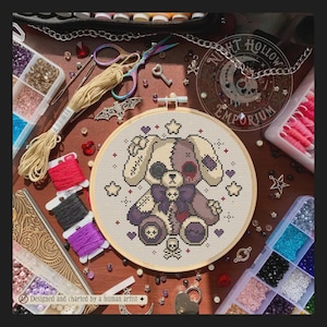 Puede incluir: Un proyecto de punto de cruz en un bastidor de madera con un conejo de patchwork y un lazo de calavera, rodeado de estrellas y corazones. Incluye hilo de bordar, tijeras, cuentas y un logotipo que dice Night Hollow Emporium.