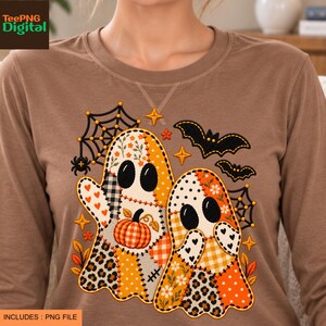 May include: A brown long-sleeve shirt featuring a graphic of two ghosts made of various patterned patches including orange, white, and black colors. The design includes a pumpkin, spiderwebs, bats, and stars in a festive autumn theme.