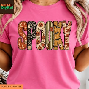 May include: A bright pink t-shirt featuring the word SPOOKY printed across the chest. Each letter has a unique pattern, including orange moons and stars, black cross-stitching, orange pumpkins, green stripes, black bats, and a brown geometric quilt design.