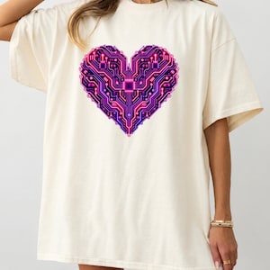 Op de afbeelding: Een gebroken wit T-shirt met korte mouwen en een grote, centrale afbeelding van een hart in de vorm van een computerprintplaat. Het ontwerp toont ingewikkelde elektronische paden in levendige tinten neonroze, paars en donkerblauw.