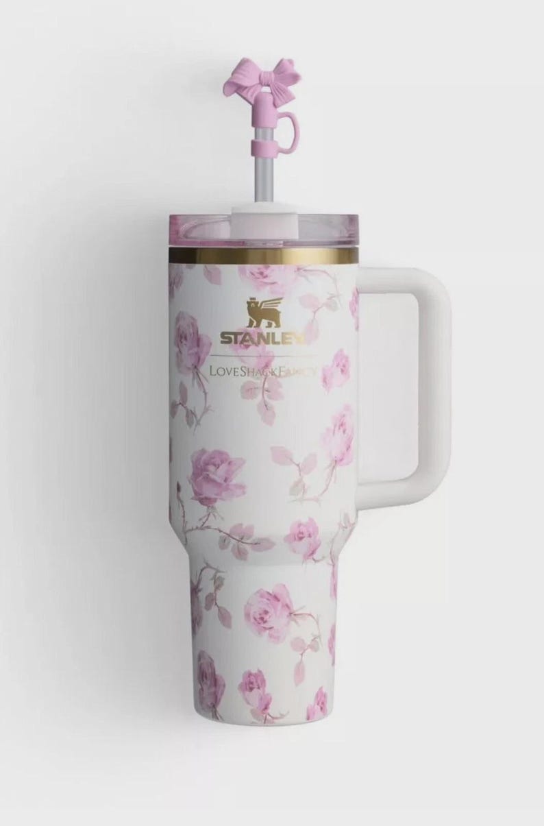 Op de afbeelding: Witte ge&iuml;soleerde beker met een rozenpatroon en een roze strik op het rietje. De beker heeft een handvat en de tekst "STANLEY" en "LOVESHAKE".