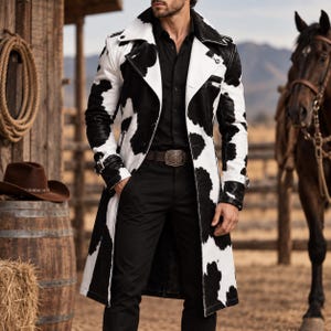 Könnte beinhalten: Ein langer Trenchcoat mit schwarz-weißem Kuhfleckenmuster, breitem Kragen und Schnallen an den Ärmelbündchen. Der Mantel wird über einem schwarzen Hemd und einer schwarzen Hose mit einer großen metallischen Gürtelschnalle getragen.