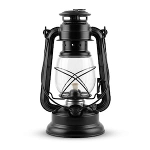 May include: A matte black hurricane lantern featuring a clear glass globe, a central wick, and a protective wire cage. The metal frame includes a top handle, a circular base, and a chimney vent at the top, designed for traditional oil-based lighting.