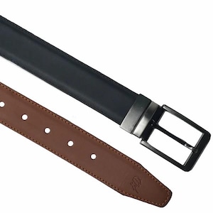 Può includere: Una cintura reversibile con un lato in pelle nera e un lato in pelle marrone. La cintura ha una fibbia color argento e diversi fori per la regolazione. Il lato marrone ha un logo in rilievo vicino alla punta.