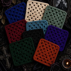 May include: A collection of nine square crochet coasters in various colors including cream, navy blue, sage green, burgundy, teal, black, purple, dark green, and burnt orange. Each coaster features a classic granny square pattern with open stitches.