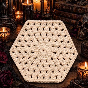 May include: A cream-colored hexagonal crochet doily featuring a dense, textured pattern of clustered stitches radiating from the center. The piece has a defined geometric shape with a consistent, repeating stitch design throughout the entire surface.