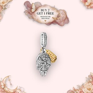 May include: A silver-toned metal charm shaped like the Millennium Falcon spaceship, featuring a bail encrusted with small clear stones and a small gold-toned tag engraved with the text STAR WARS, suspended from a central jump ring.