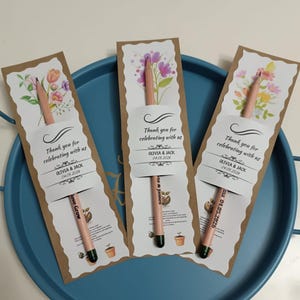 Pu&ograve; includere: Tre matite con bustine di semi, ognuna con disegni floreali e la scritta "Thank you for celebrating with us", i nomi Olivia & Jack e la data 04.05.2026. Le matite hanno la punta verde e la scritta "Love Grow".