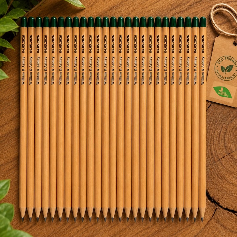 Puede incluir: Un juego de veinticuatro l&aacute;pices de madera de color marr&oacute;n claro con gomas de borrar de color verde oscuro. Cada l&aacute;piz tiene impreso el texto William & Ashley 04.05.2026. Una etiqueta de cart&oacute;n beige con un logo Eco Friendly est&aacute; atada.