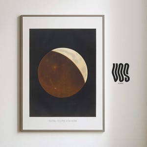 May include: A framed wall art print featuring a partial lunar eclipse against a dark background. The moon is depicted with a reddish-brown shadow and a bright crescent. The text at the bottom reads PARTIAL ECLIPSE of the MOON, with VOS studio to the right.