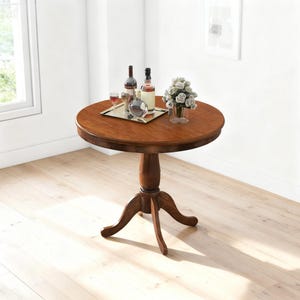 May include: A round, dark brown wooden side table with a pedestal base and three curved legs. The table is topped with a tray holding two wine bottles, two glasses, and a decorative glass sphere. A vase of white flowers sits on the table.