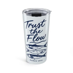 Puede incluir: Un vaso de acero inoxidable blanco con tapa de plástico transparente y cierre deslizante negro. El exterior presenta el texto azul oscuro Trust the Flow, un gráfico de tres peces apilados y el texto Numen Soul en la parte inferior.