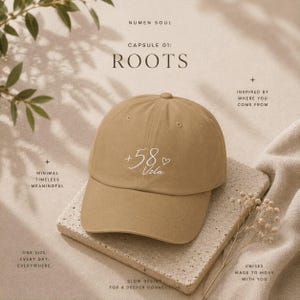 May include: A tan baseball cap featuring the white embroidered text +58 and Vzla with a small heart symbol. The cap has a structured crown and a curved brim. The text is centered on the front panel of the hat, which is displayed on a textured surface.