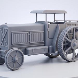 May include: A grey model of a vintage tractor. The tractor has large spoked wheels, a detailed radiator, and a small roof. The design includes a driver's seat and a storage box. The overall aesthetic is reminiscent of early 20th-century farm equipment.
