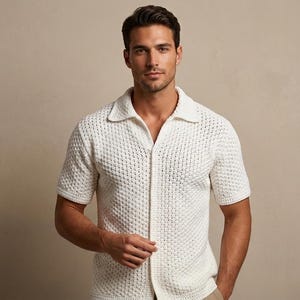 Op de afbeelding: Crèmekleurige polo met korte mouwen en een textuurgebreid patroon. De polo heeft een klassieke kraag en een knoopsluiting aan de voorkant. Het kledingstuk is gemaakt van een ademende stof, geschikt voor warm weer. Dit shirt is een veelzijdige aanvulling op elke garderobe.