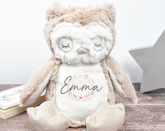 May include: A beige plush owl with closed eyes and a white belly. The owl has a floral wreath with the name "Emma" embroidered on its chest.